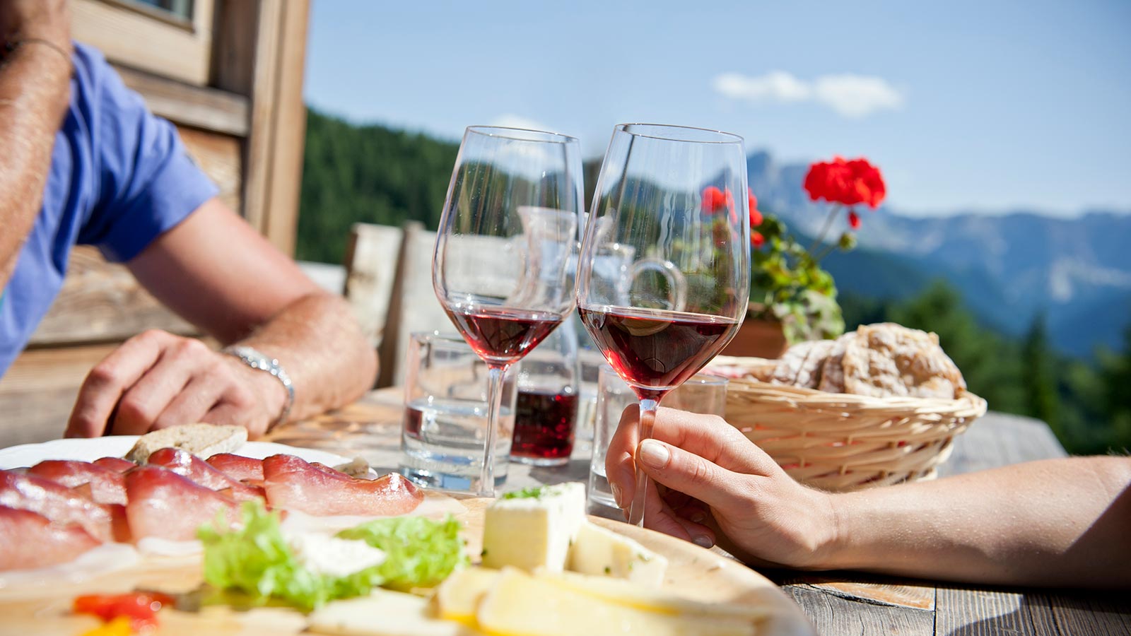 Due ragazzi bevono due calici di vino e mangiano piatti tipici all'hotel Der Wiesenhof